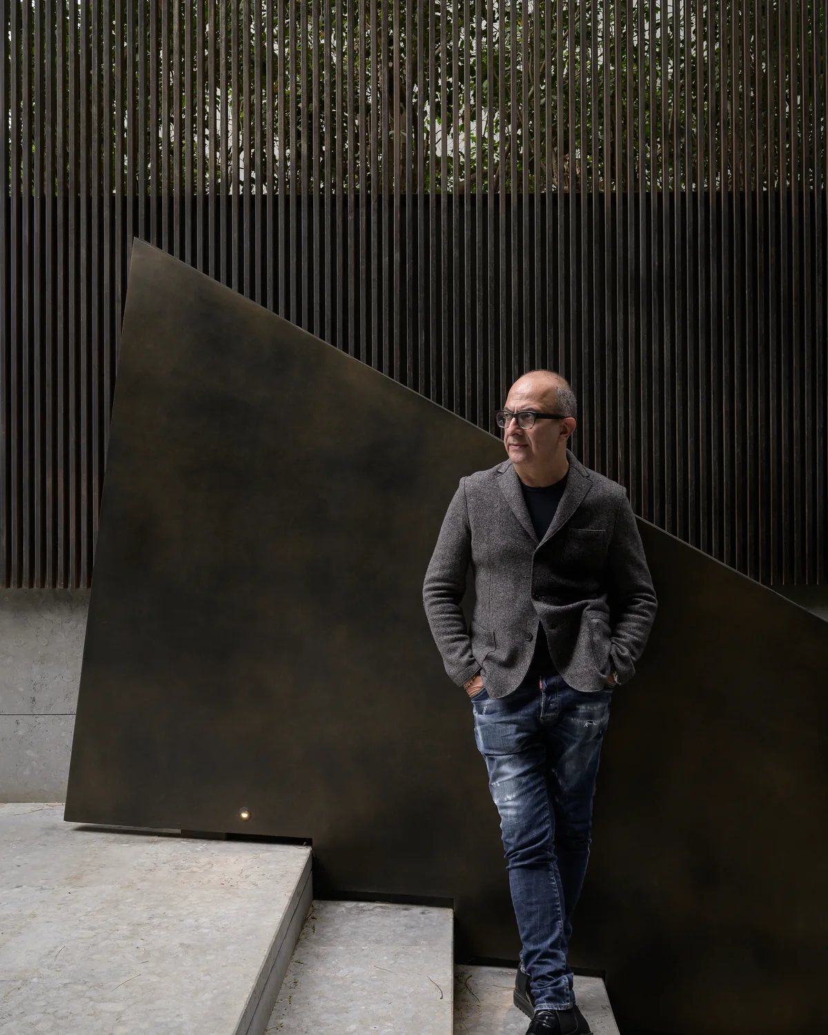 Karim Mekhtigian against a bronze plane in the studio courtyard